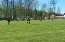 Zawodnicy podczas meczu na boisku. W tle park 